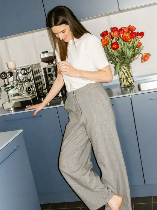 Frau in grauer Hose in einer blauen Küche