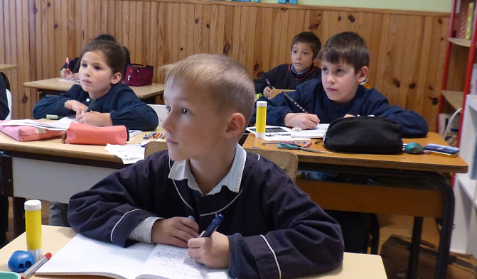 Élèves attentifs en pleine séance d'apprentissage en classe, concentrés sur leurs cahiers et exercices.