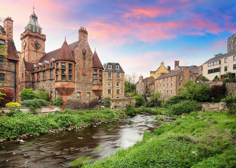 Historic stone buildings and a clock tower line a river under a pink-blue sunset sky, with lush green banks.
