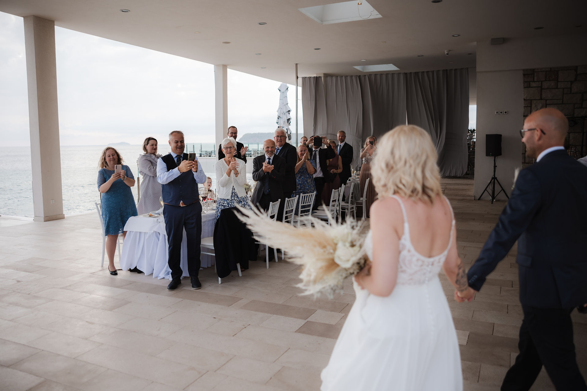 the bride and groom come to the terrace of the restaurant where guests are waiting for them