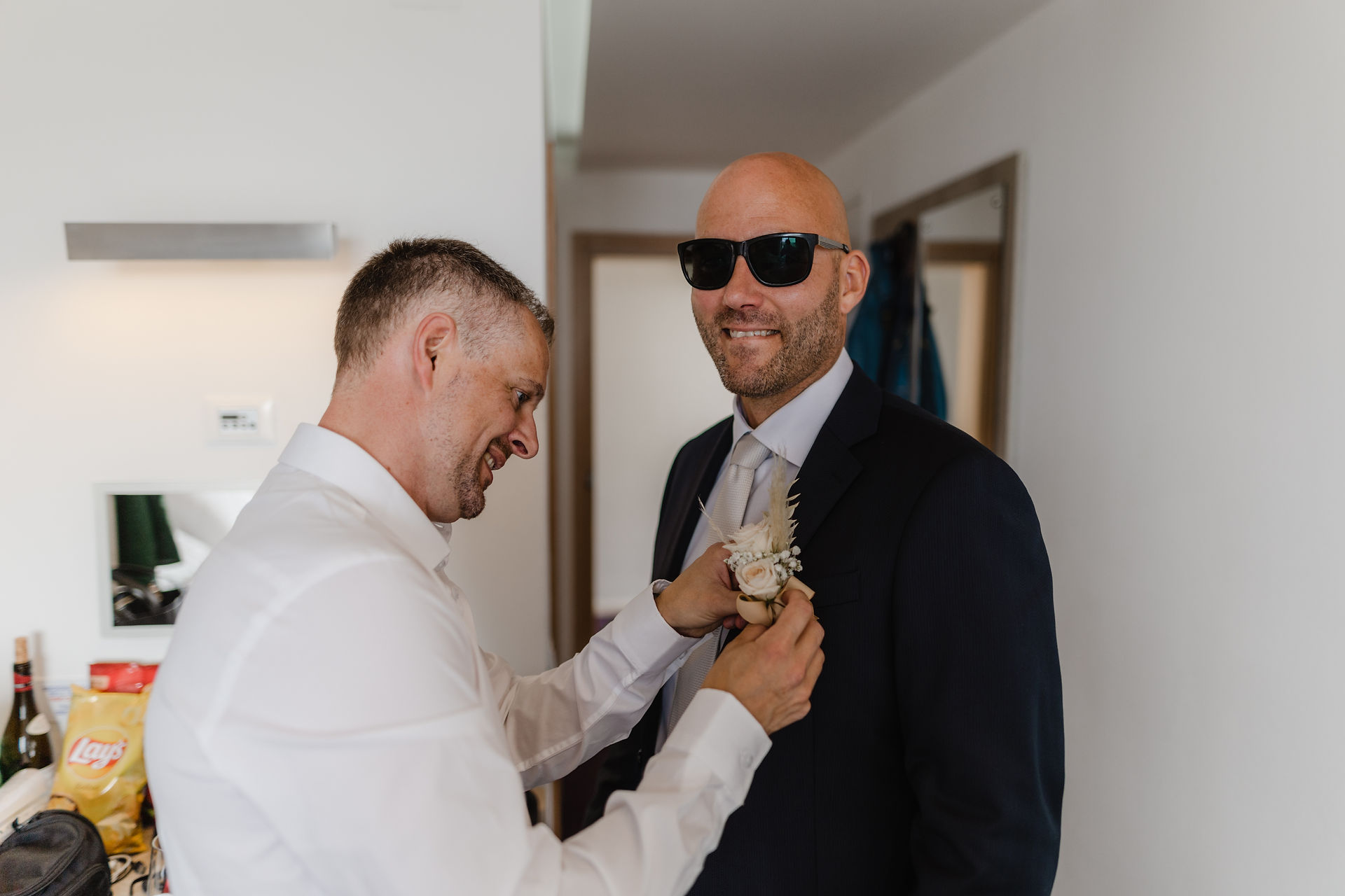 the best man helps the groom with his jacket