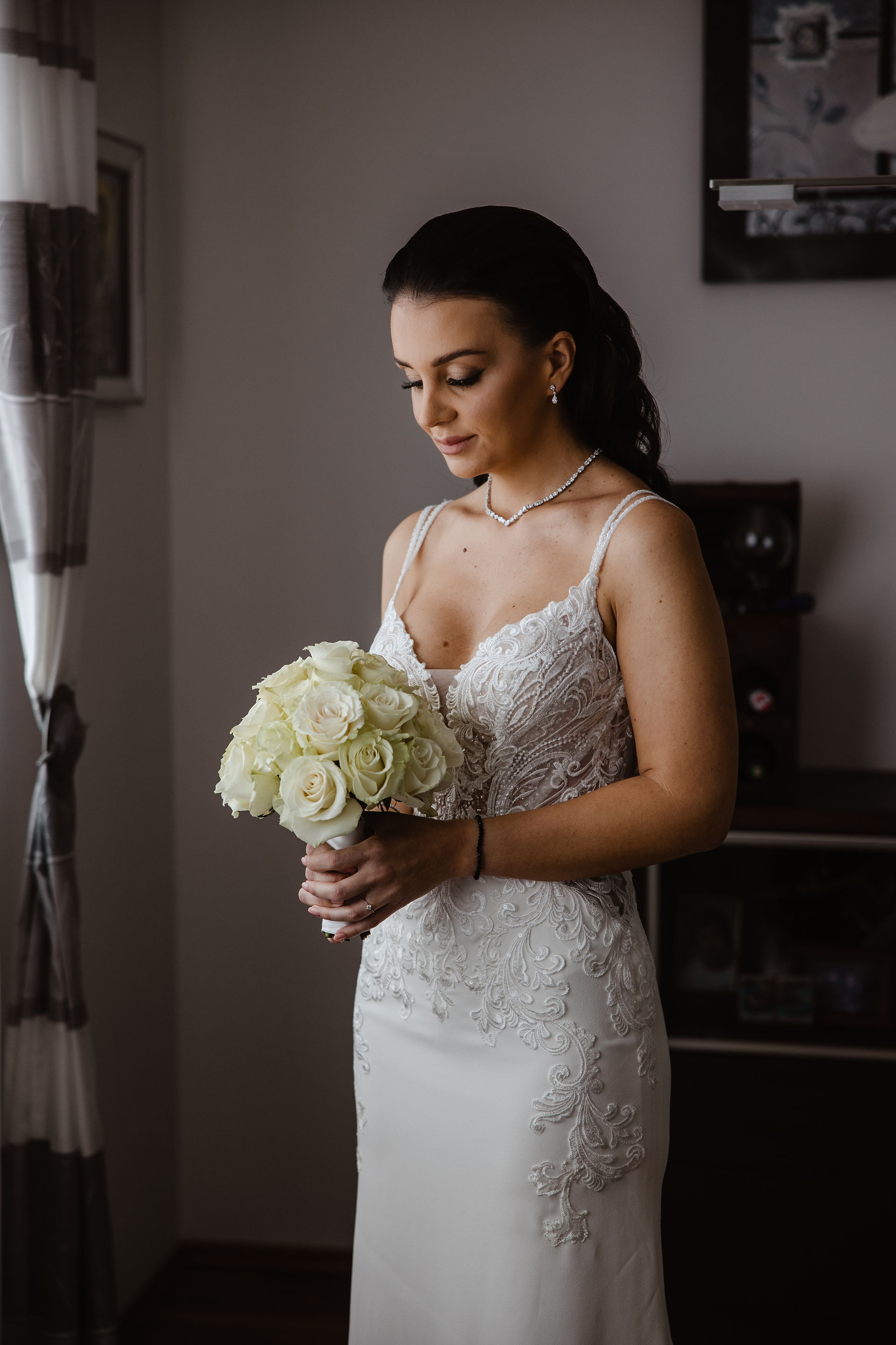 the bride in her wedding dress looks at the bouquet