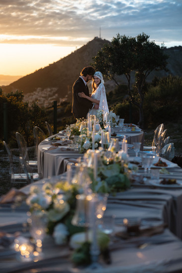 Editorial wedding portrait of a bride and groom sharing a quiet moment at a long, candlelit reception table during the blue hour at Park Orsula, Croatia.