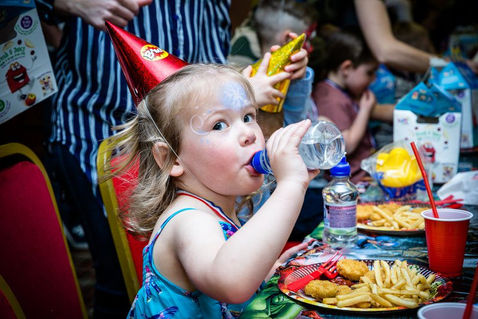 Private Social Events: Children at a birthday party enjoy the festivities. Table of party food for kids.