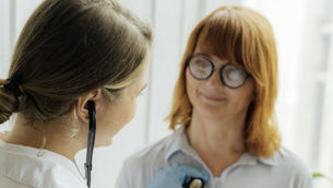 A doctor is using a stethoscope and talking with a patient