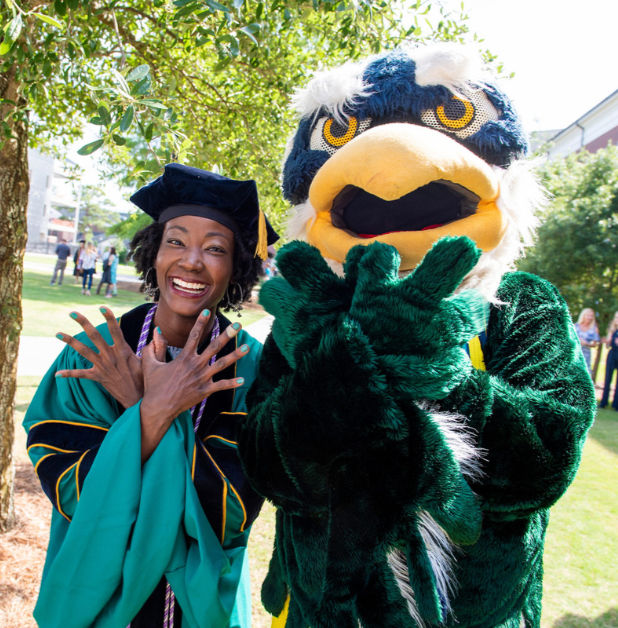 UNCW graduate with UNCW mascot on graduation day