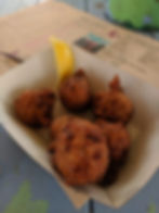 a paper basket of conch fritters with lemon