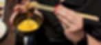 a woman is dipping beef into a raw egg bath with chopsticks
