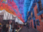 rainbow colored banners above a street market
