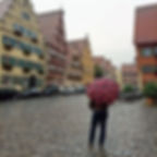 a man stands with an umbrella in a charming Germany town