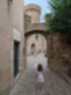 girl looking at a castle tower and gate in tossa de Mar vila vella