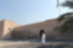 man in Omani dress in front of clay colored castle