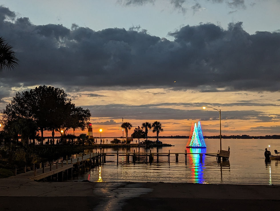 a lake at sunset with a lighthouse and Christmas trees