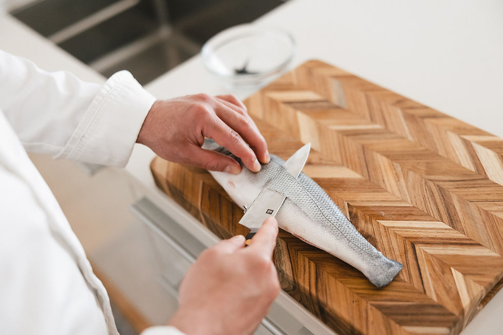 Chef Victor Rivera filleting a silver fish on a herringbone wooden cutting board in a bright kitchen