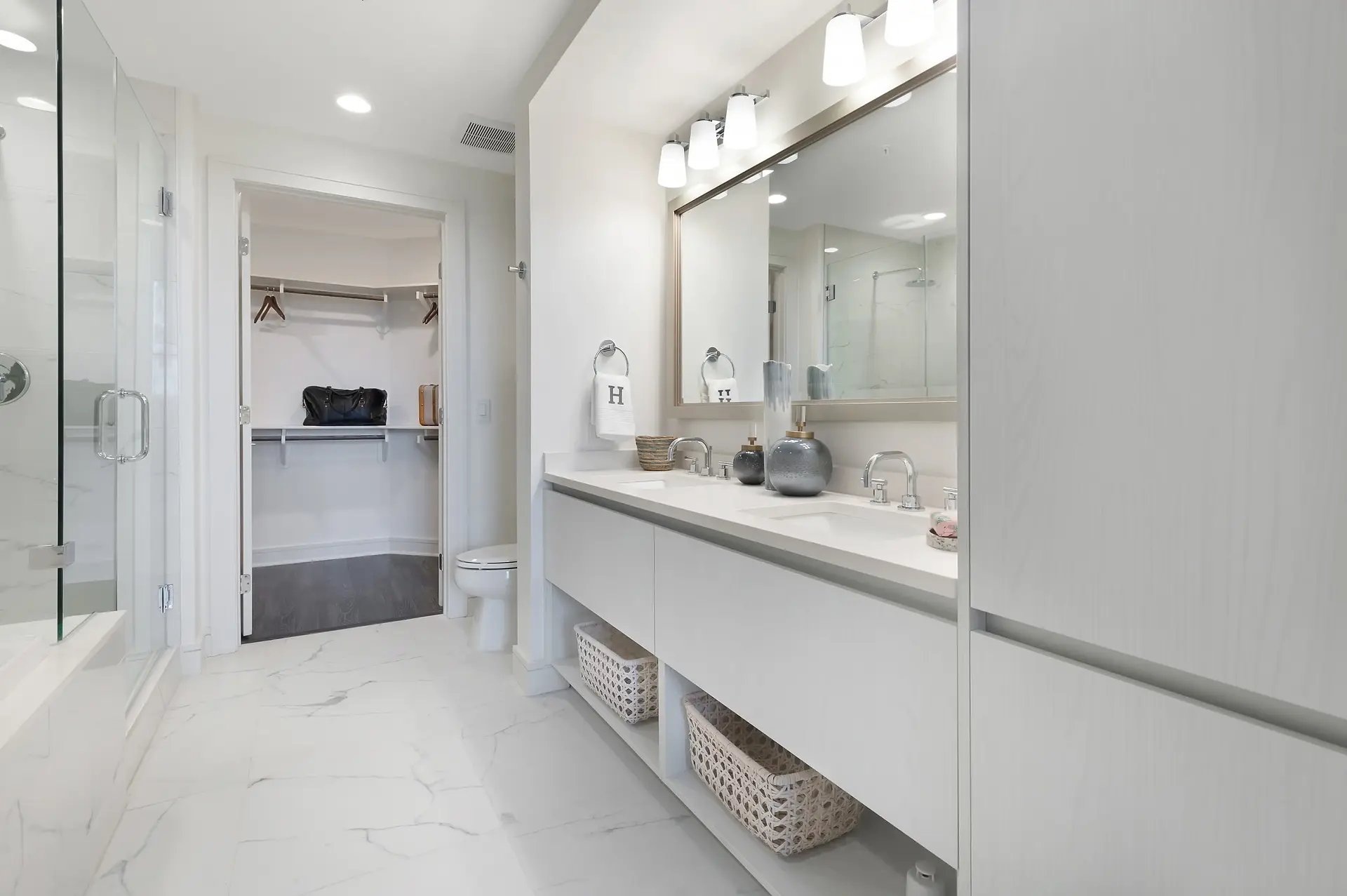 Modern bathroom with double vanity, walk-in closet, and marble flooring