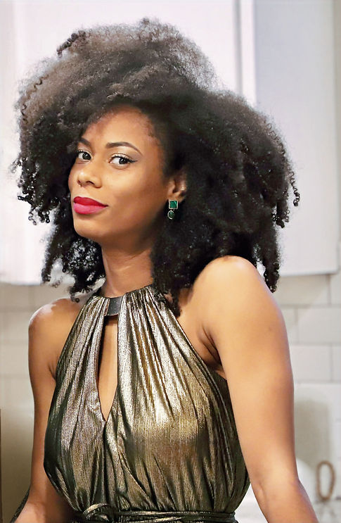 Close-up of woman with big curly afro hair in golden dress by Akira Chicago, small gold Banana Republic earrings with green stone on the cover of travel magazine for sisterhood and travel talks about luxury for black women, stylish travel destinations, and encourages readers to travel with style and purpose. She’s wearing ruby Woo lipstick by MAC and winged-eyeliner. The magazine has content on Caribbean women travel stories and present luxury fashion editorials along with travel photography.