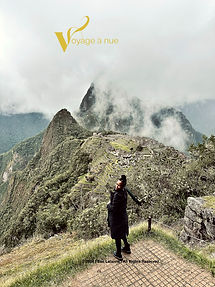 Woman in black trench coat points to machu picchu in cuzco peru