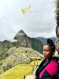 travel blogger with afro hair poses with machu picchu in the background under cloudy skies