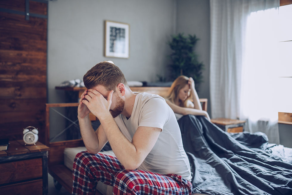 A couple sits apart on their bed with their heads in their hands after the man has experience performance anxiety