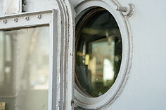 Close-up of a weathered ship door and round porthole window Reflections of light and blurr