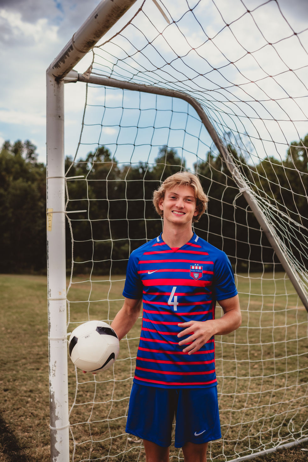 A soccer player holding a ball near the goal.