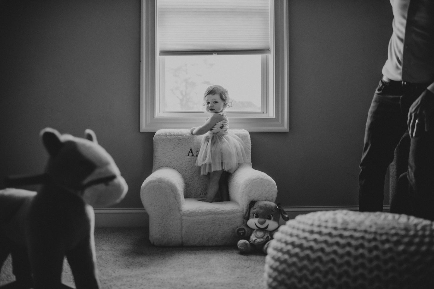 Authentic family photo of a child standing on chair in cozy room in black and white.