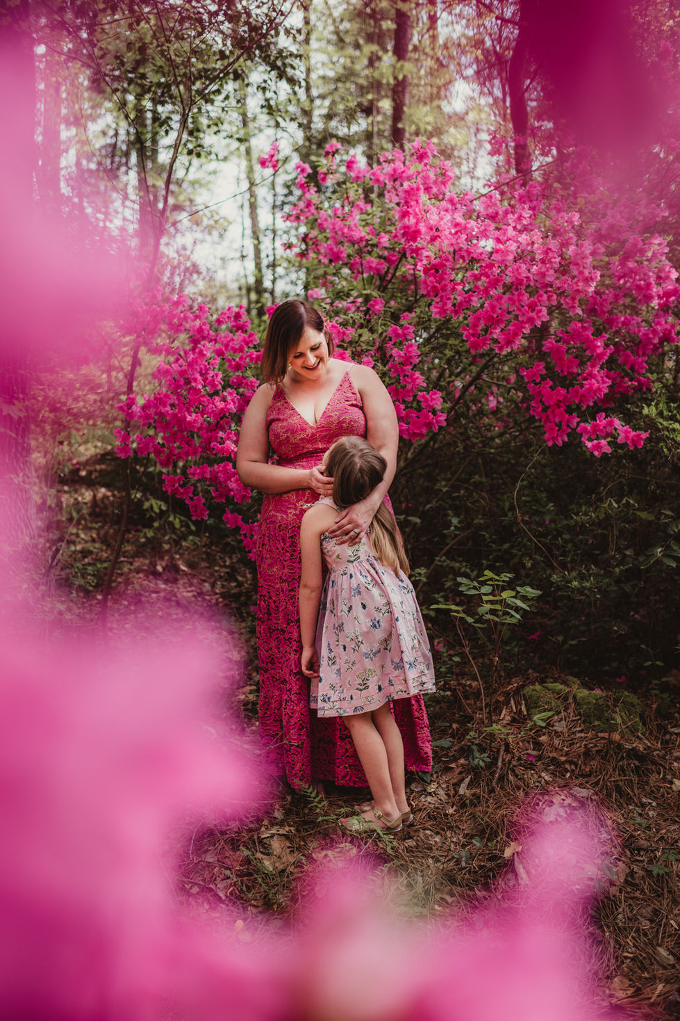 Woman and child surrounded by vibrant pink flowers.