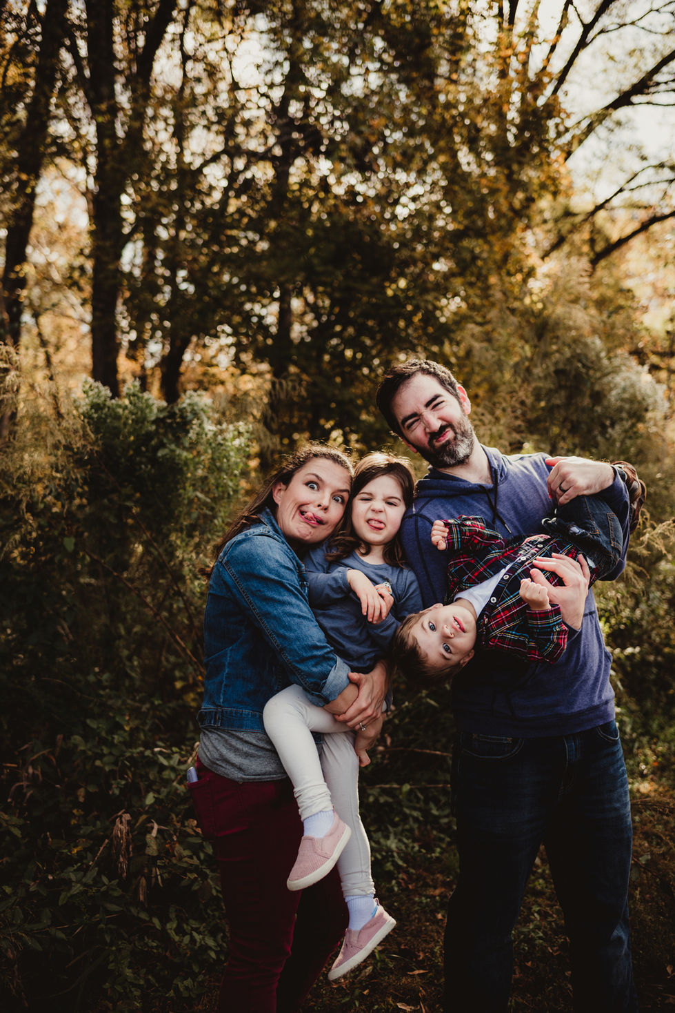 Family posing playfully in a wooded area.
