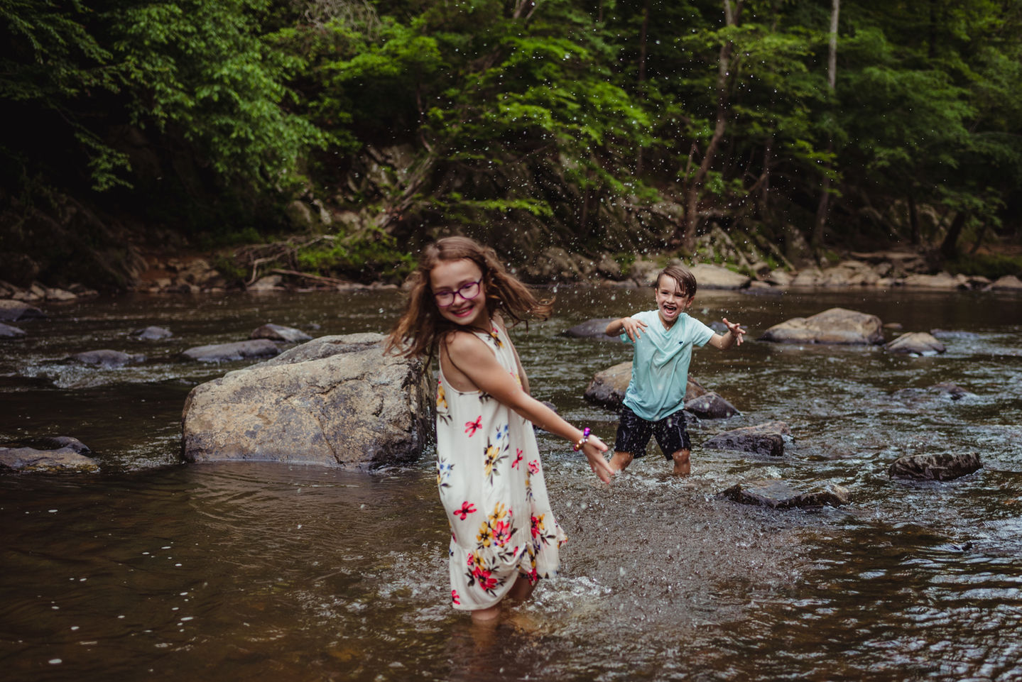 Two children playing in a forest stream.