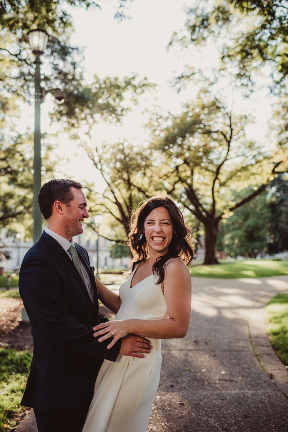 a candid portrait of a groom smiling at the bride smiling at the camera