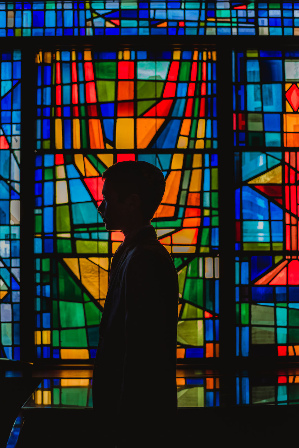 Silhouette of person against colorful stained glass window in a synagogue.