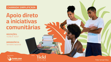 Foto com três pessoas jovens negras, estando duas em pé e uma sentada, todas em frente a um notebook sobre uma mesa que ainda tem uma pilha de livros. Ao lado esquerdo da foto, tem os textos "Chamada simplificada Apoio diretos a iniciativas comunitárias", "Inscrições de 15/06 a 14/07" e "Abrangência Território nacional".