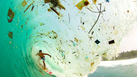 Foto mostra surfista dentro de uma onda marinha em formato de tubo com lixo por todo o caminho dela.