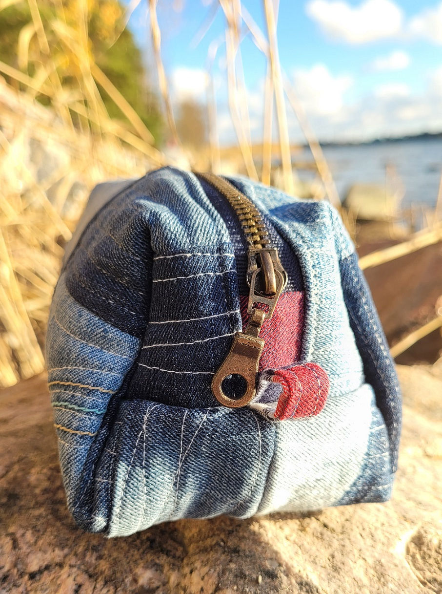 Close-up of the handmade quilted denim pouch with the zipper closed, showing the zipper pull and denim zipper tabs.