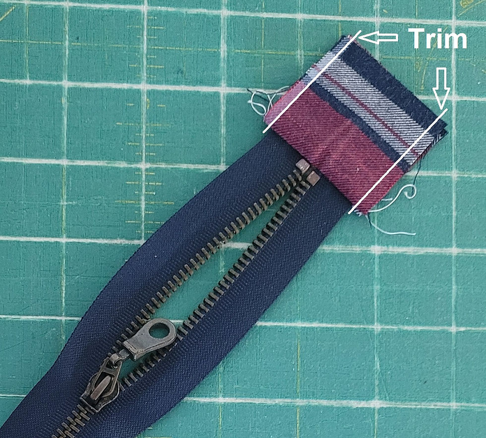 Trimming zipper tabs on the zipper for a handmade quilted denim pouch.