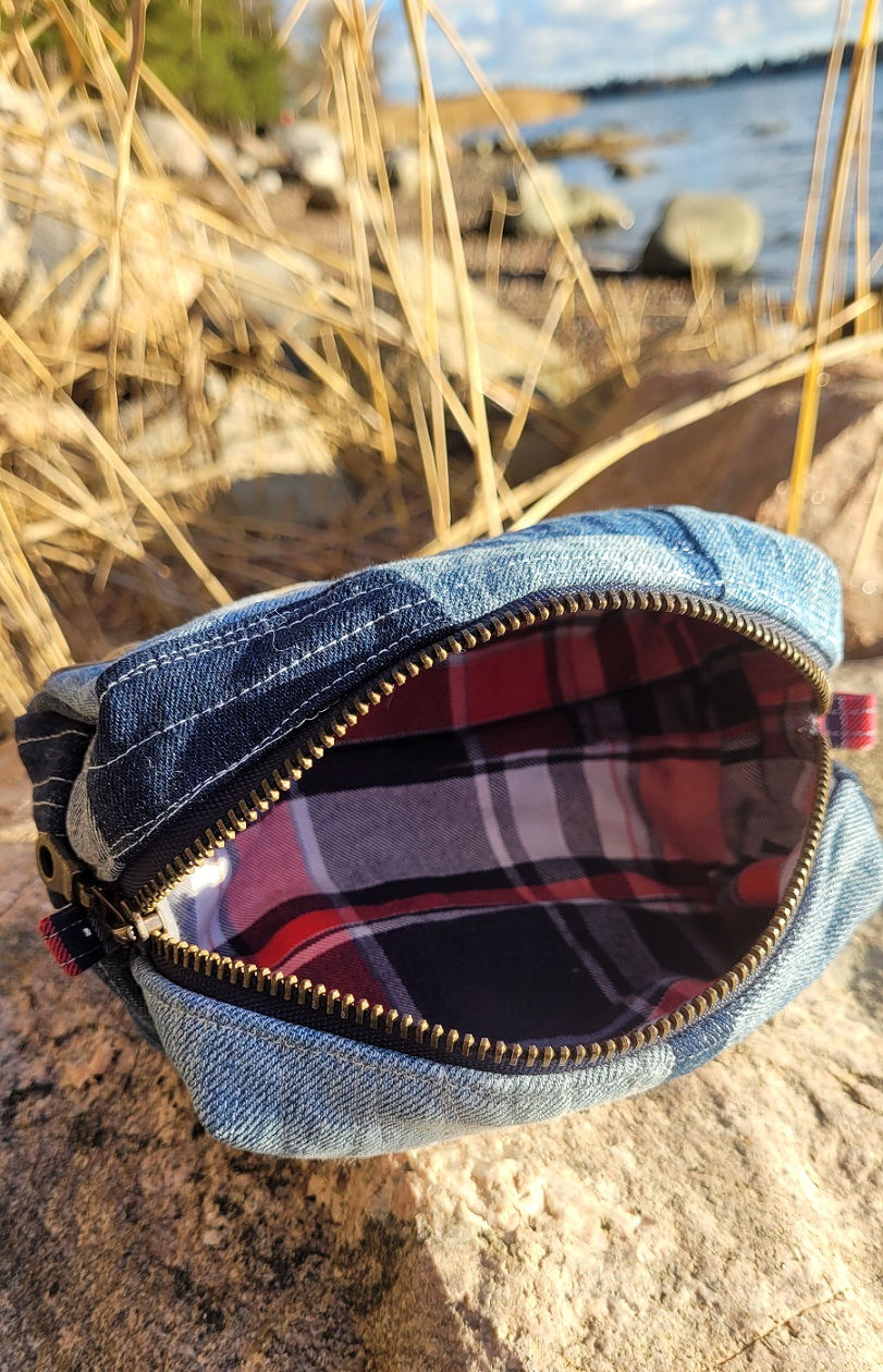 Handmade quilted denim pouch with the zipper open, showing the fabric lining and spacious interior.