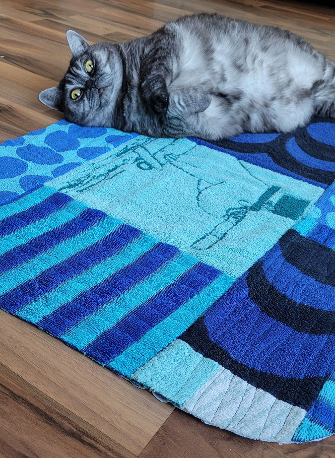 Cat lying on a DIY bathroom rug made from old towels