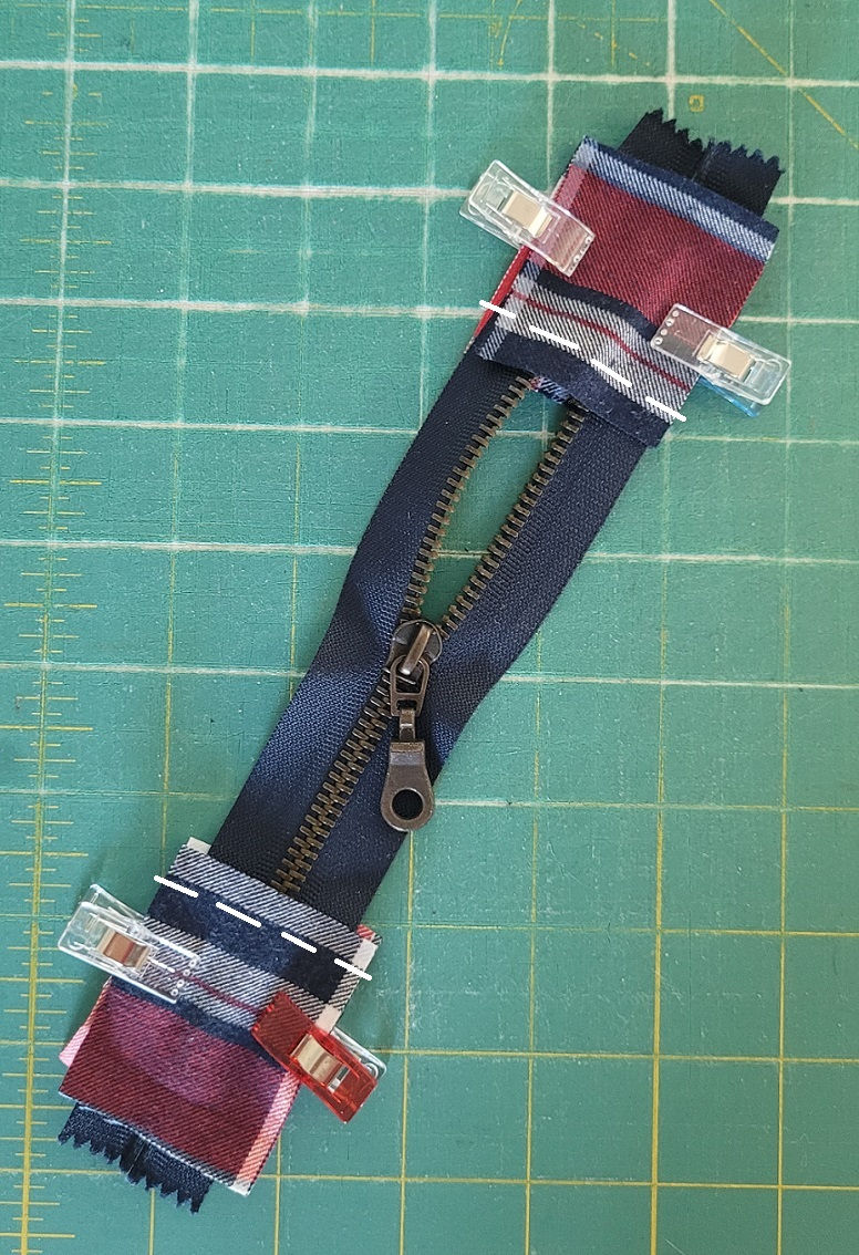 Adding zipper tabs to the zipper for a handmade quilted denim pouch.
