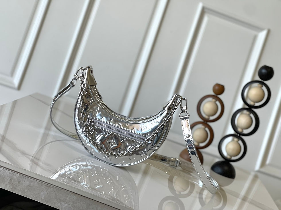 Shiny silver Louis Vuitton half-moon handbag on a reflective surface – Lux Studio USA.