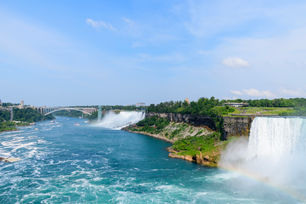 a waterfall with a bridge in the background