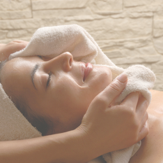 A woman receiving a facial treatment, eyes closed and at rest.