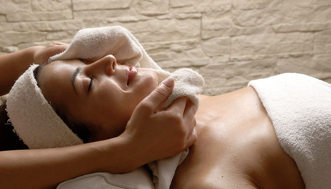 A guest receiving a holistic facial treatment — eyes closed, fully at rest