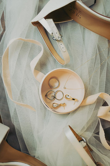 A top-down view of a bride's details on her wedding day, including her shoes, veil, and jewelry with ribbons around it