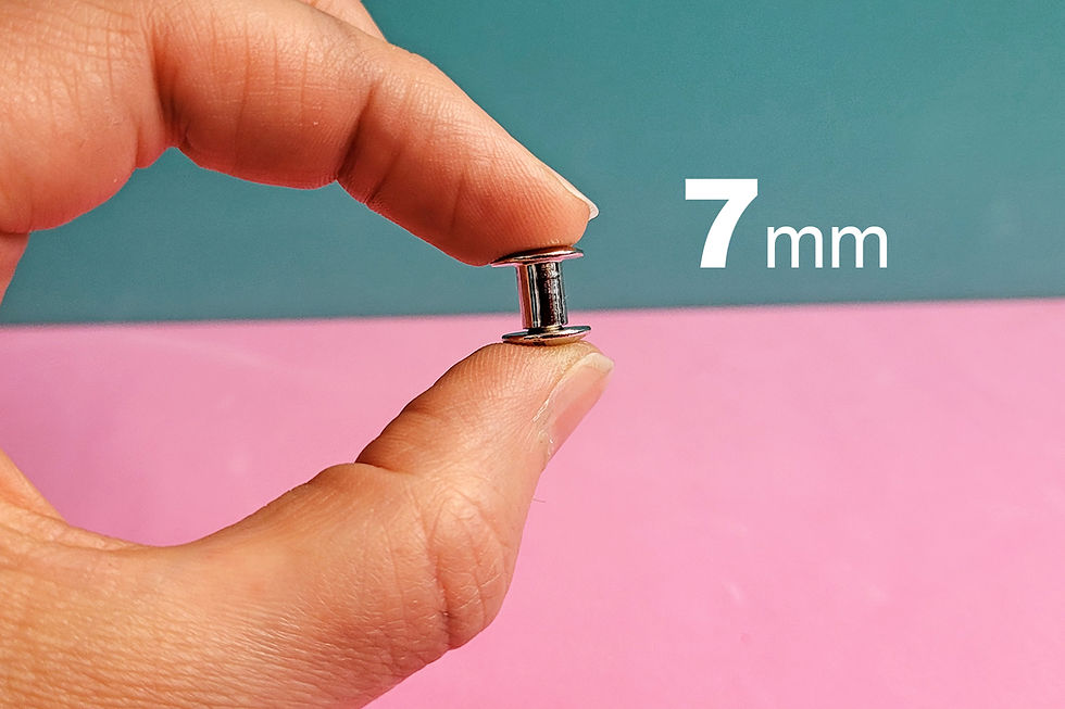 Miniaturbild: Eine Hand hält eine Buchschraube mit 7mm Schaftlänge zwischen den Fingern