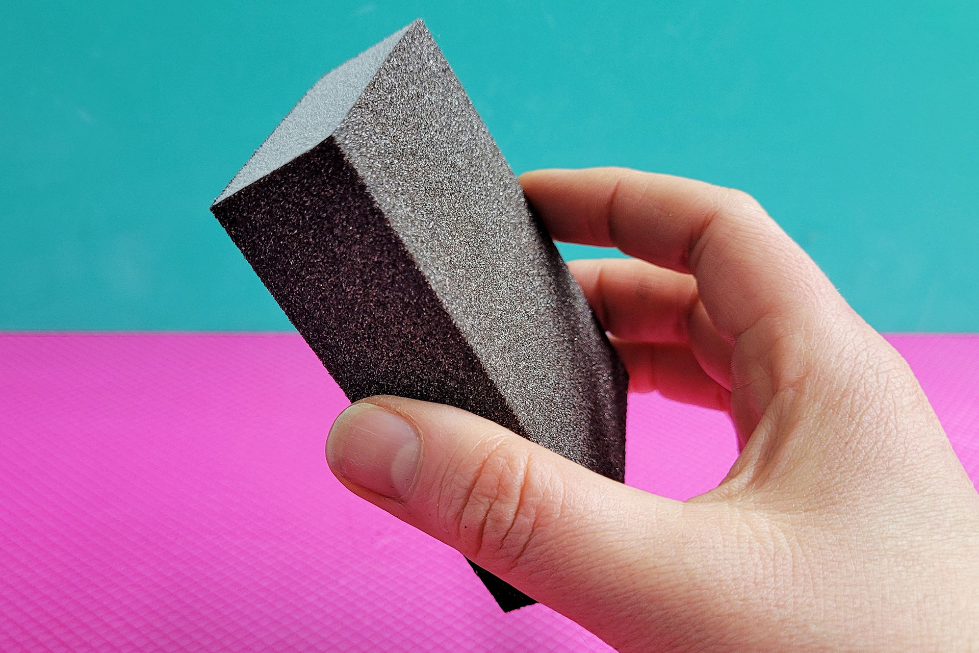 Eine hand hält einen block-artigen Schleifschwamm