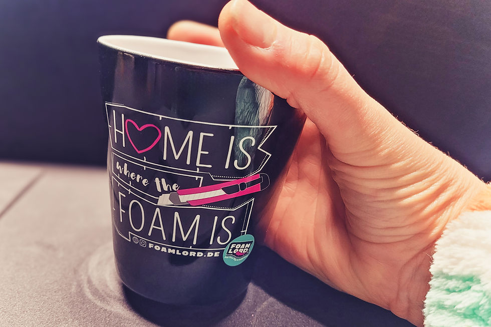 Miniaturbild: Eine Hand hält eine schwarze Tasse mit der Aufschrift "Home is where the Foam is"