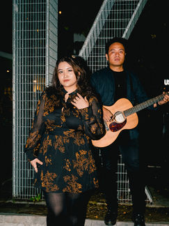 Kamila Batavia posing outdoors with a guitarist during a night performance for The Scent of Camellias tour.
