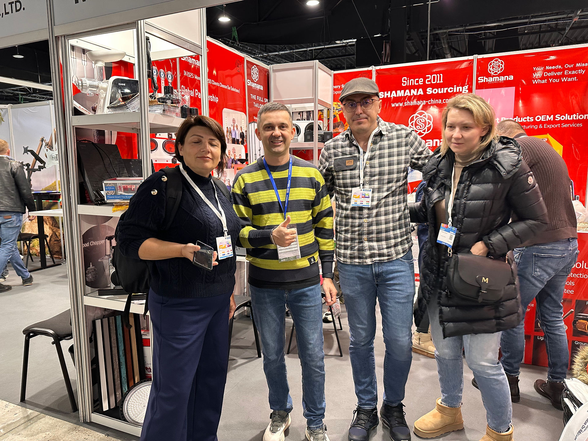 Estande da SHAMANA Sourcing na AES PTAK Expo Warsaw 2025 – vista frontal com visitantes na área de eletrônicos e eletrodomésticos.
