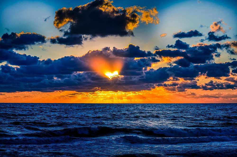 Sunset forming a silhouette of a heart in the clouds over the ocean