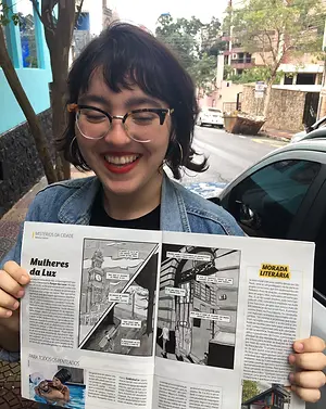 Cecilia Marinas segurando a Veja SP, com uma matéria sobre Parque das Luzes, Jornalismo em Quadrinhos.